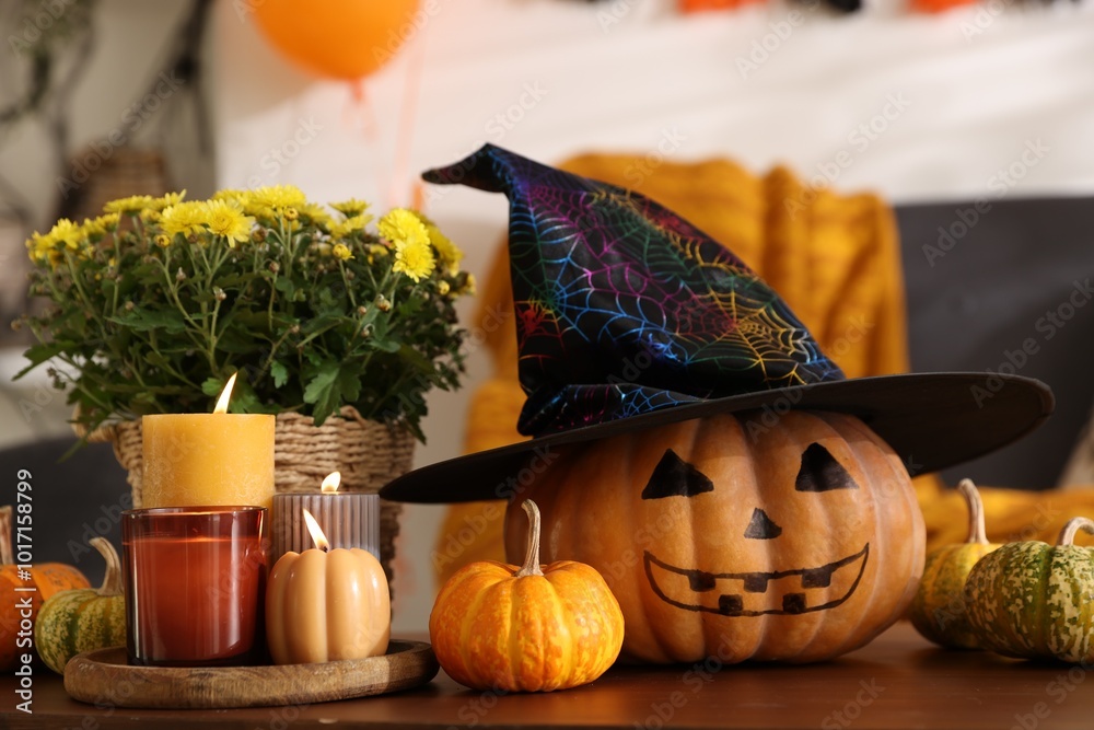 Wall mural Burning candles, flowers and pumpkins on table in room decorated for Halloween