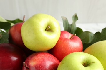 Ripe apples and green leaves on table, closeup