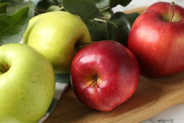 Ripe apples and green leaves on table, closeup