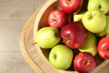 Ripe red and green apples in bowl on wooden chair, top view