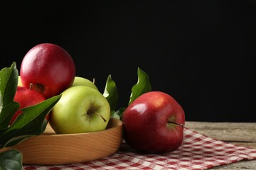 Ripe apples and green leaves on wooden table. Space for text