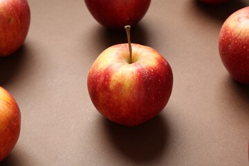 Ripe red apples on brown background, closeup