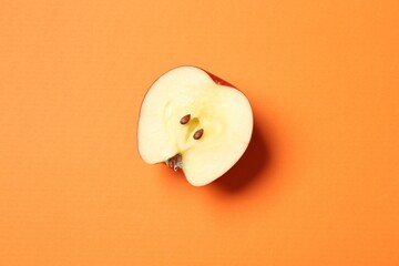 Cut fresh red apple on orange background, top view