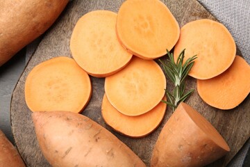 Fresh raw sweet potatoes and rosemary on table, top view