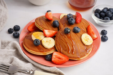 Tasty pancakes with blueberries and banana on white background