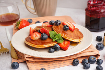 Tasty pancakes with blueberries and strawberry on white background