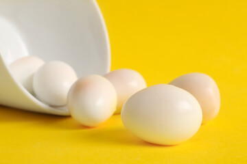 Bowl with fresh boiled quail eggs on yellow background