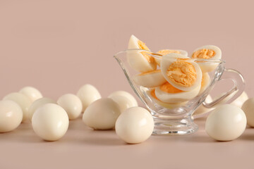 Gravy boat with cut fresh boiled quail eggs on grey background
