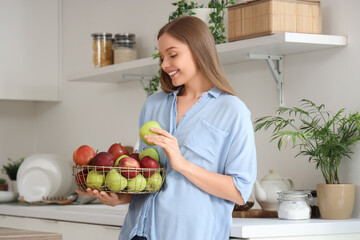 Young woman with basket of apples in kitchen