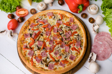 High angle view of homemade pizza on wooden table surrounded by vegetables, mushrooms and cheese