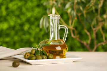 Decanter of fresh olive oil on white table outdoors