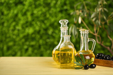 Decanters and bottle of fresh olive oil on wooden table outdoors