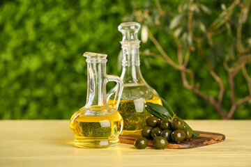 Decanters of fresh olive oil on wooden table outdoors