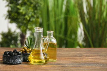 Olives with oil on wooden table against blurred background
