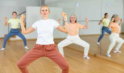 Obraz premium Woman doing squats with her family on group fitness training in studio.