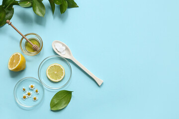 Petri dishes with plants and ingredients for preparing natural cosmetics on blue background