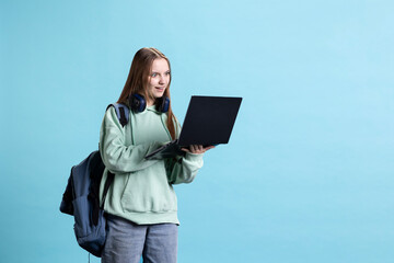 Obraz premium Upbeat teenager opening laptop, excited to start job shift, isolated over studio background. Portrait of radiant girl with notebook ready to do business related tasks on it