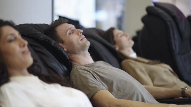 Adult people is sitting in a massage chair and enjoying a massage at the shopping mall after a working day. Concept. 4K.