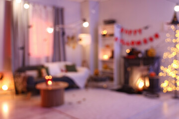 Blurred view of dark living room with grey sofa, fireplace and Halloween decorations