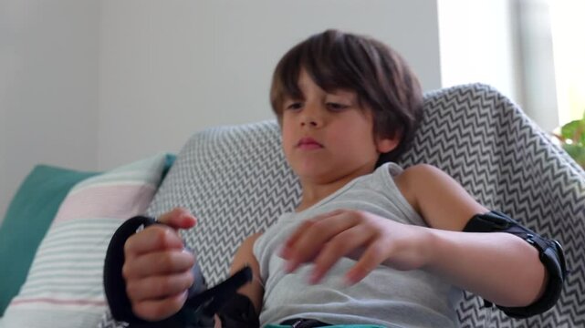 Young boy adjusting his elbow pad while sitting on the couch, focusing on making sure it fits correctly. concentration and patience in getting ready for an active outdoor adventure