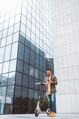 A man rides an electric scooter around the city in front of the glass building where he works