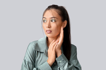 Beautiful young Asian woman with stylish mint makeup on grey background