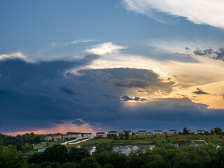 Warm sunglow at sunset over American neighborhood with dark thunder storm clouds approaching.