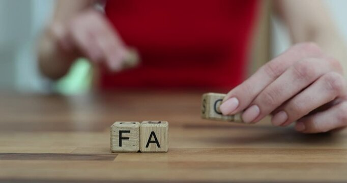 Woman hand flips wooden cubes changing word Fake to Fact. Concept of media literacy in modern world to avoid misinformation by verifying