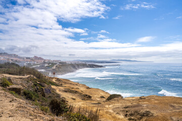 The Atlantic Ocean in Ericeira Portugal with Waves and the Town on the Coastline.