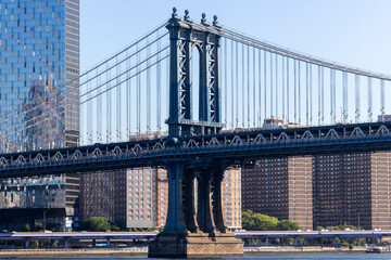 A view of the Williamsburg Bridge spanning the East River in New York City, with urban buildings in the background, showing the city's iconic infrastructure