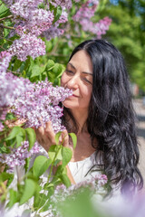 Fototapeta premium Woman enjoys fragrant lilac blossoms, peaceful moment in nature, serene outdoor scene, blossoming beauty in spring, relaxation concept