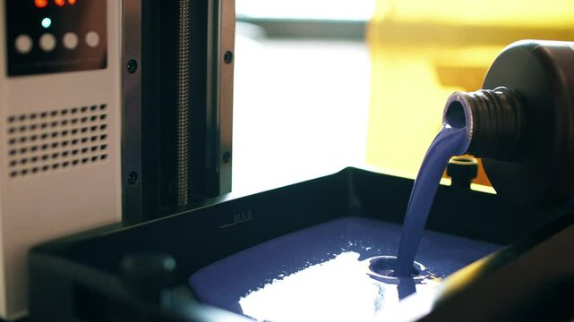 Pouring liquid resin into vat of a modern SLA 3D printer. Preparation for 3D printing or additive manufacturing