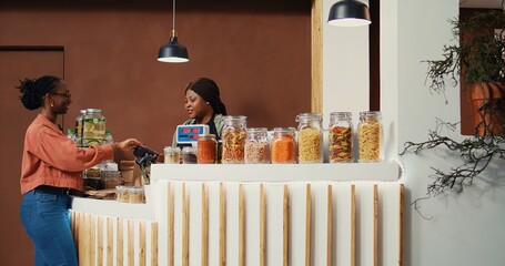 Shopper making card payment at supermarket cash register, buying fresh ripe fruits and vegetables...