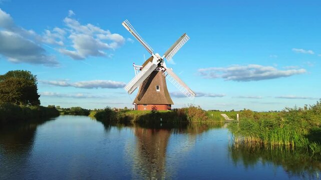 beautiful wooden windmill at sunset in the Dutch village. the beautiful dutch cannals filled with water with boat passing