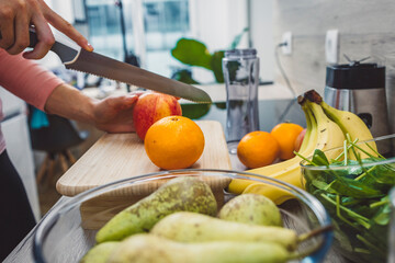 Healthy eating lifestyle concept photo of young woman preparing drink with fruit and vegetables at home in kitchen.