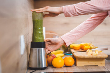 Healthy eating lifestyle concept photo of young woman preparing drink with fruit and vegetables at home in kitchen.