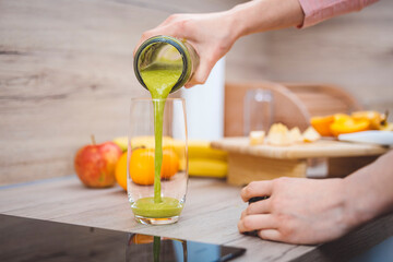Healthy eating lifestyle concept photo of young woman preparing drink with fruit and vegetables at home in kitchen.