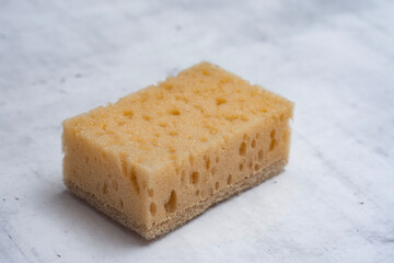 Natural coconut sponge on a marble table. Dishwashing accessory made of natural materials.