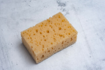Natural coconut sponge on a marble table. Dishwashing accessory made of natural materials.