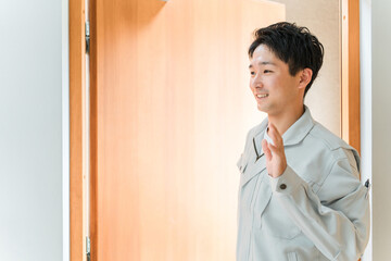 出勤時に妻に挨拶する若い作業服姿の男性
