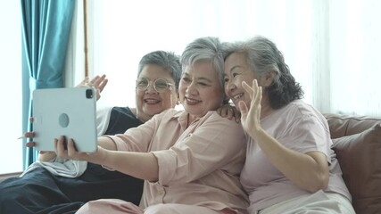 Three elderly women sit closely together, smiling and chatting. Their joyful expressions highlight a strong sense of companionship and friendship in a warm, supportive setting.