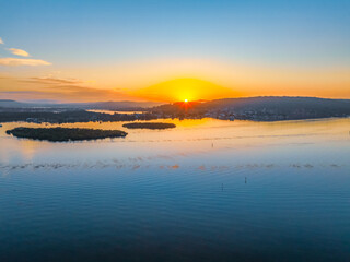 Fototapeta premium Sunrise along the waterfront with reflections on the bay water
