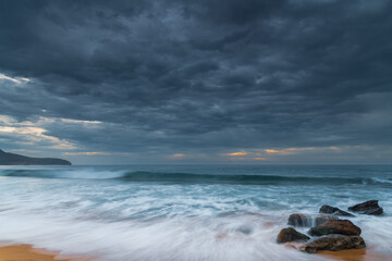 Sunrise at the seaside with rocks and beautiful diffused light by the rain clouds