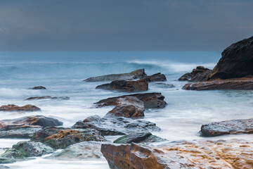 Sunrise at the seaside with rocks and beautiful diffused light by the rain clouds
