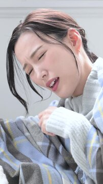自宅で風邪や発熱で喉の痛み、体調不良で具合の悪い、咳込む女性の縦動画