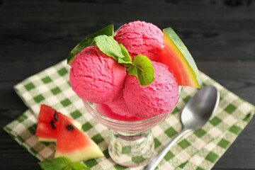 Scoops of tasty watermelon sorbet in glass dessert bowl with fresh fruit and spoon on black table, closeup