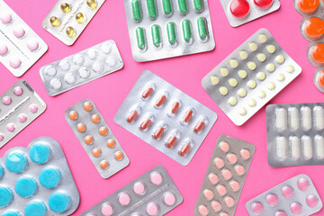 Pharmacist concept. Flat lay composition with many different pills on pink background