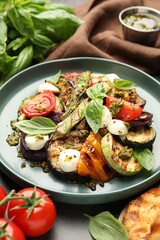 Delicious salad with grilled vegetables, pesto sauce and basil on table, closeup