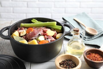 Cooking stew. Uncooked meat and vegetables in pot on white tiled table
