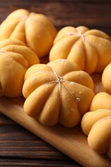 Raw pumpkin shaped buns on wooden table, closeup